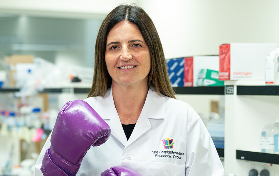 Researcher in white lab coat with purple boxing gloves
