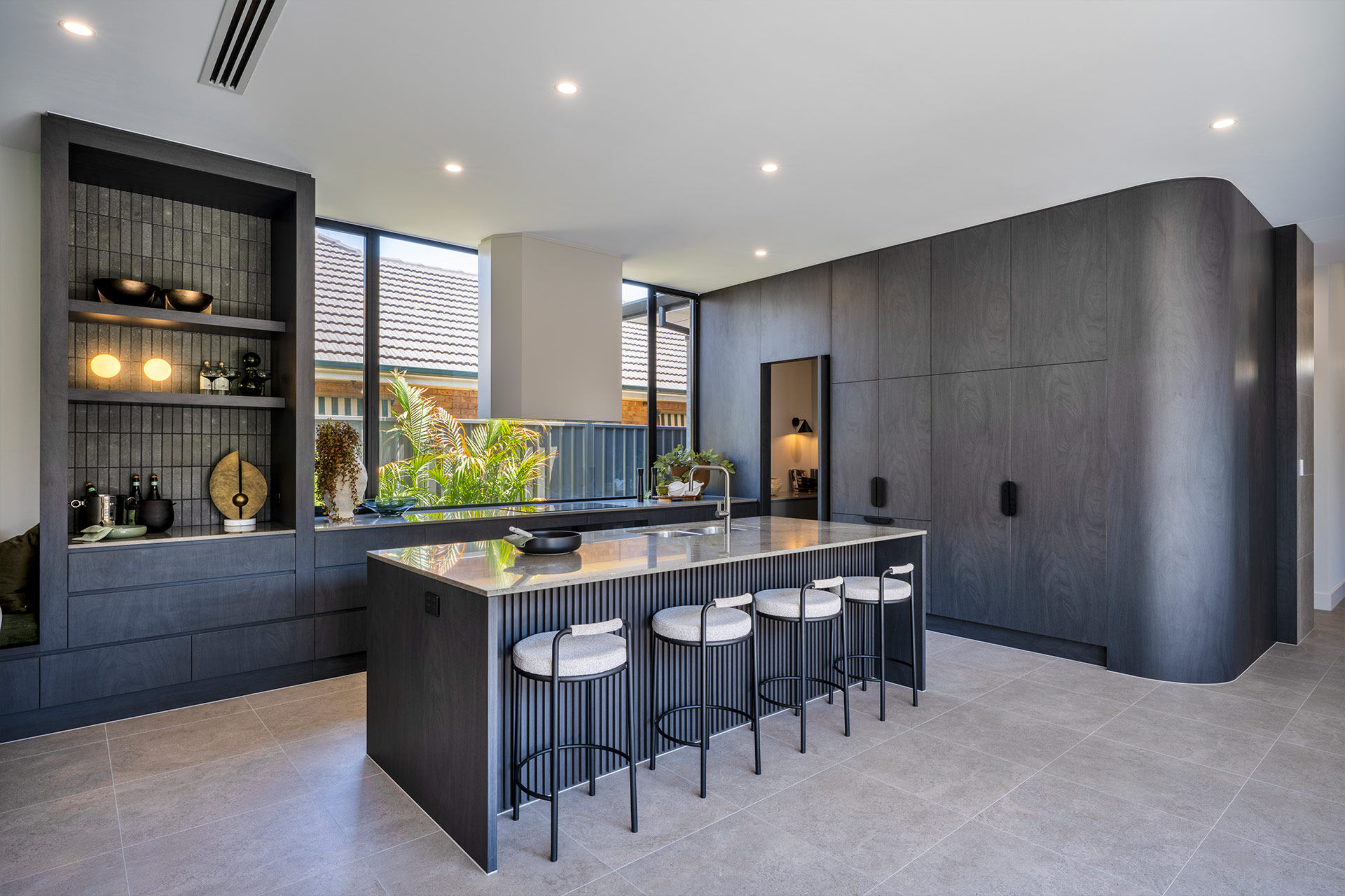 Grand Prize home kitchen with dark cabinetry and feature window splashback