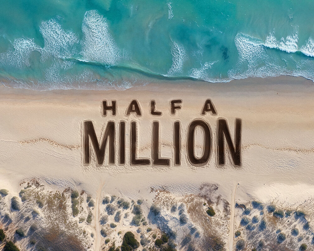Ariel view of beach with Half A Million written in the sand waves crashing