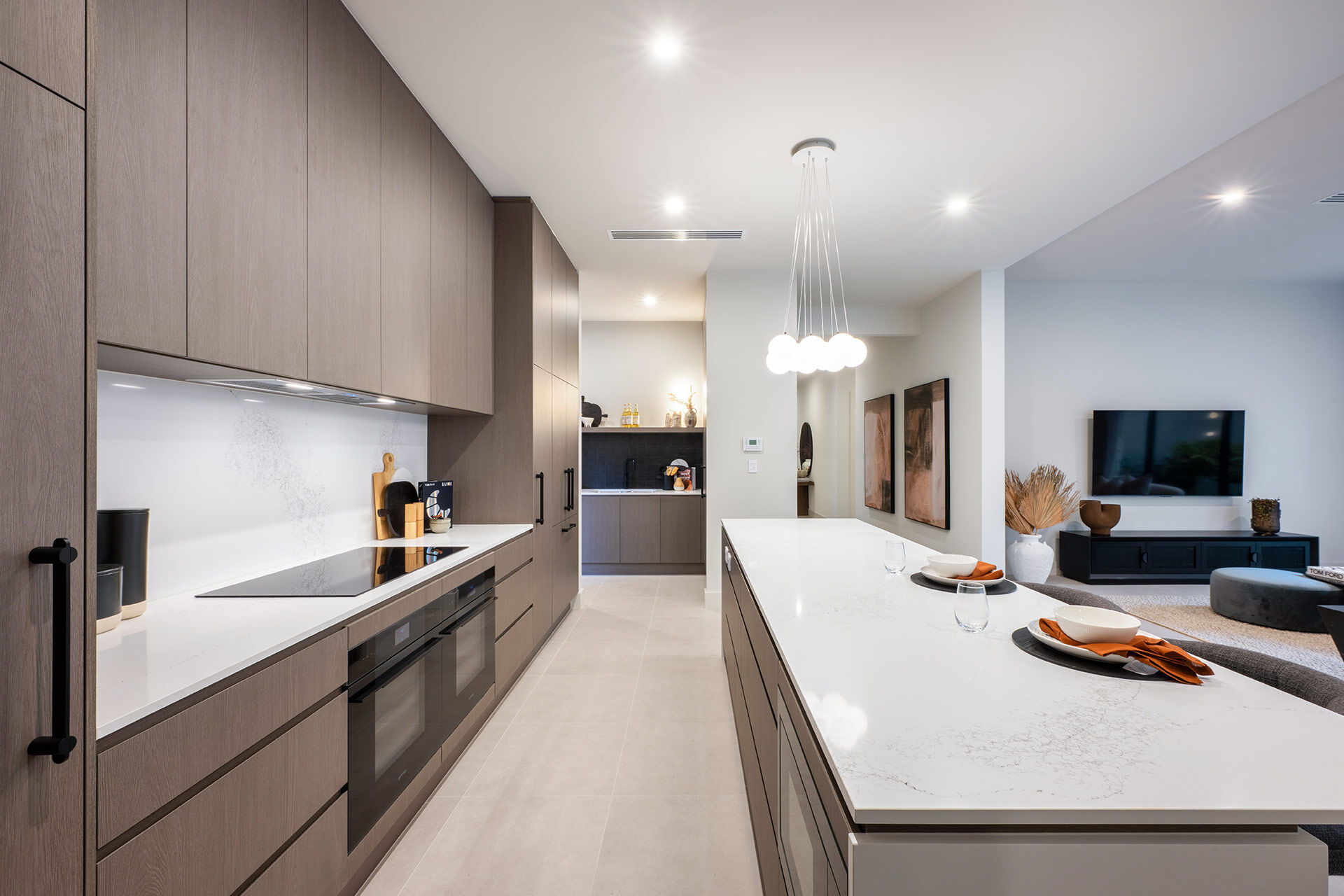 Kitchen back wall and island bench with brown cabinetry and white stone benchtops