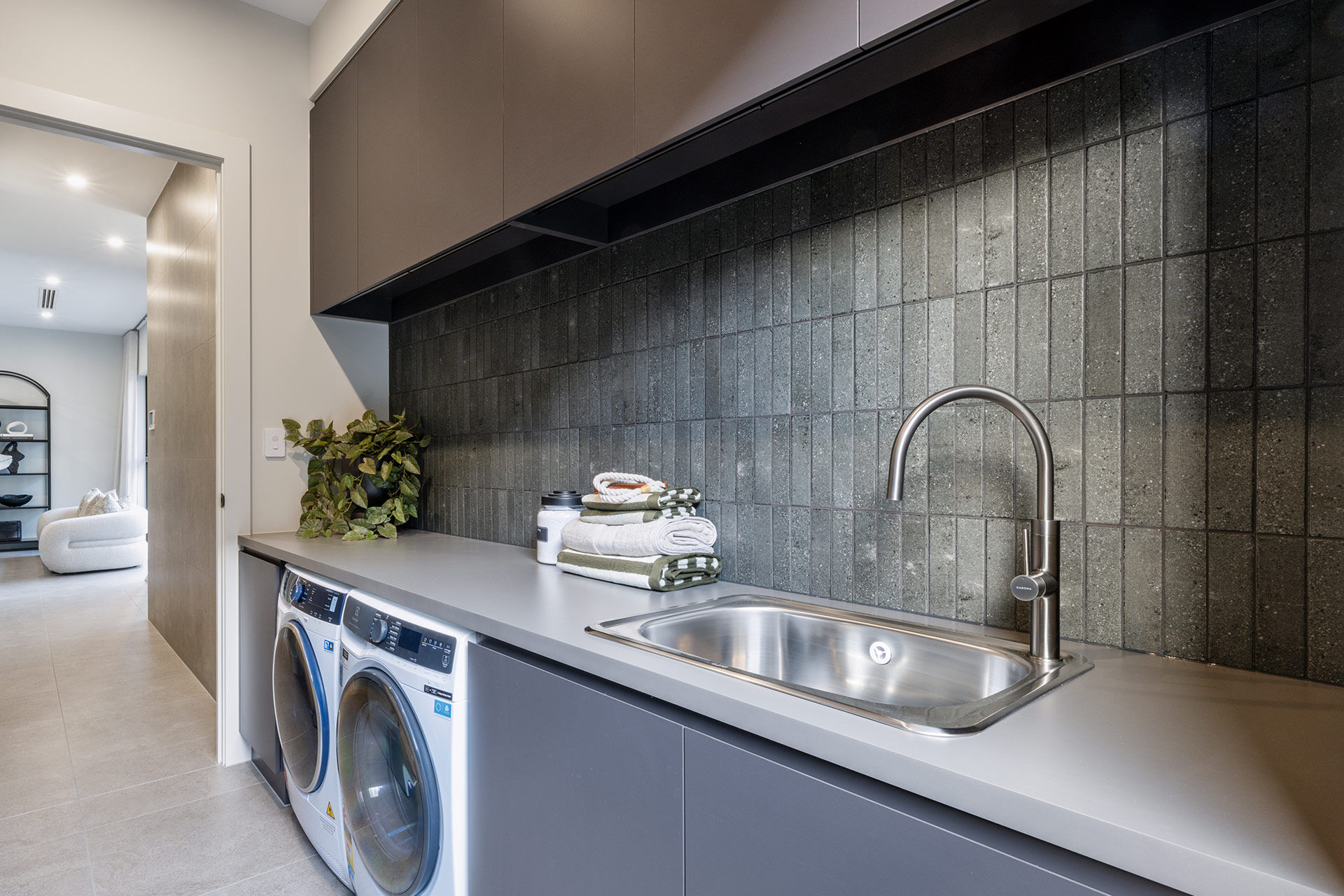 Grand Prize laundry room with dark grey tiles with brushed steel sink and tapware